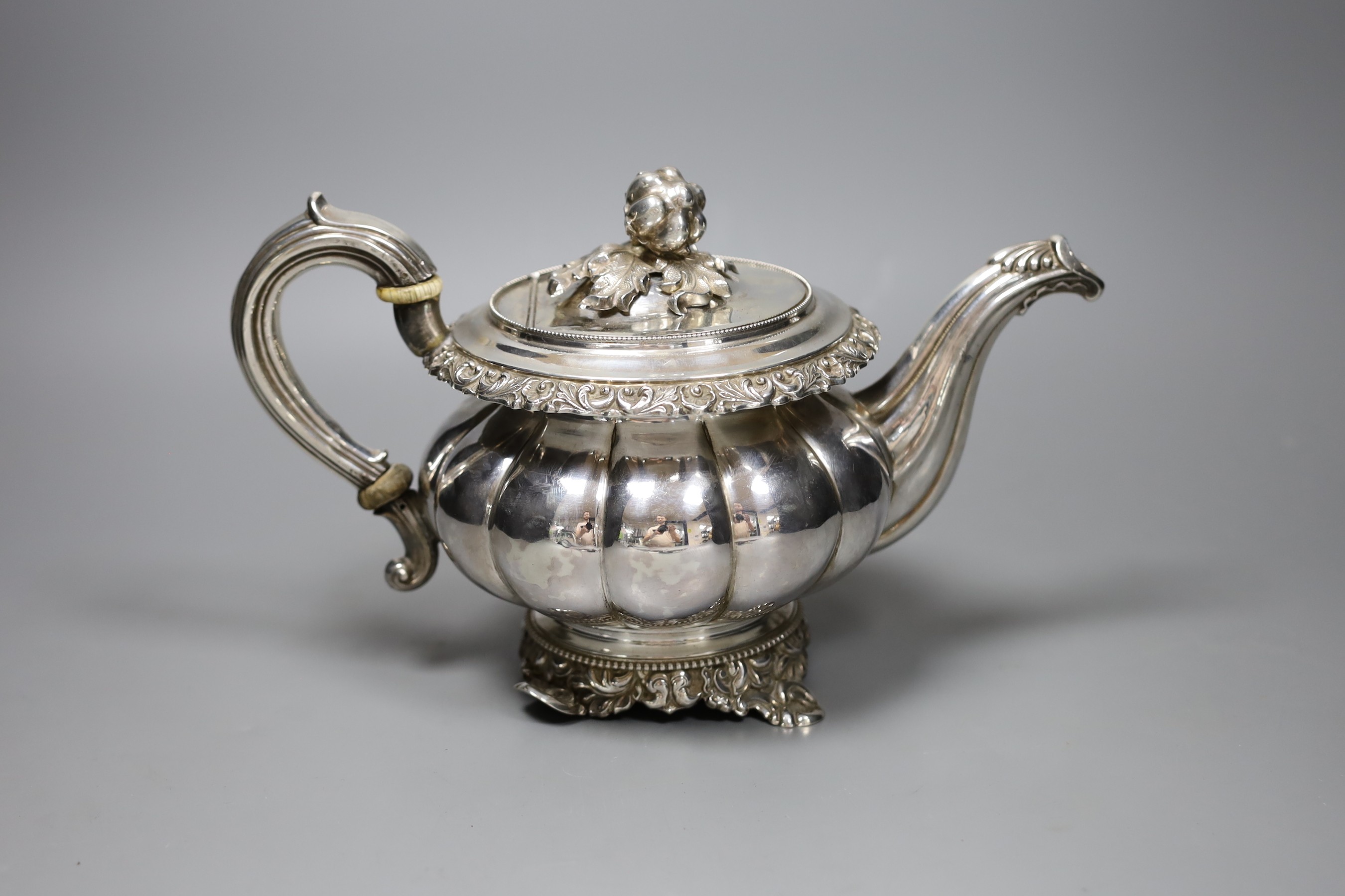 A 19th century Continental white metal teapot, with fruit finial, bone isolators and scroll feet, (a.f.), gross 24 oz.